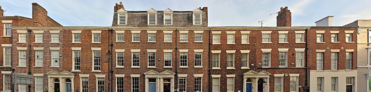 A long terrace of four-storey Georgian brick houses with sash windows and pedimented doorcases.